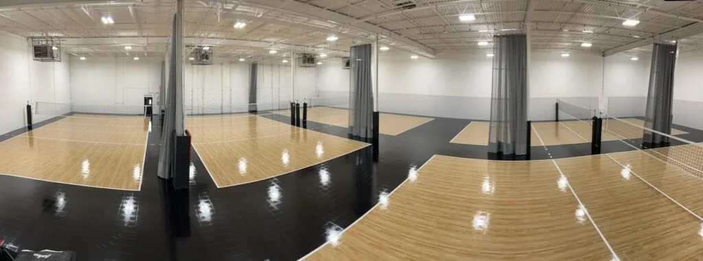 Indoor volleyball courts with nets, dividers and padded structural columns at Pakmen Courts.