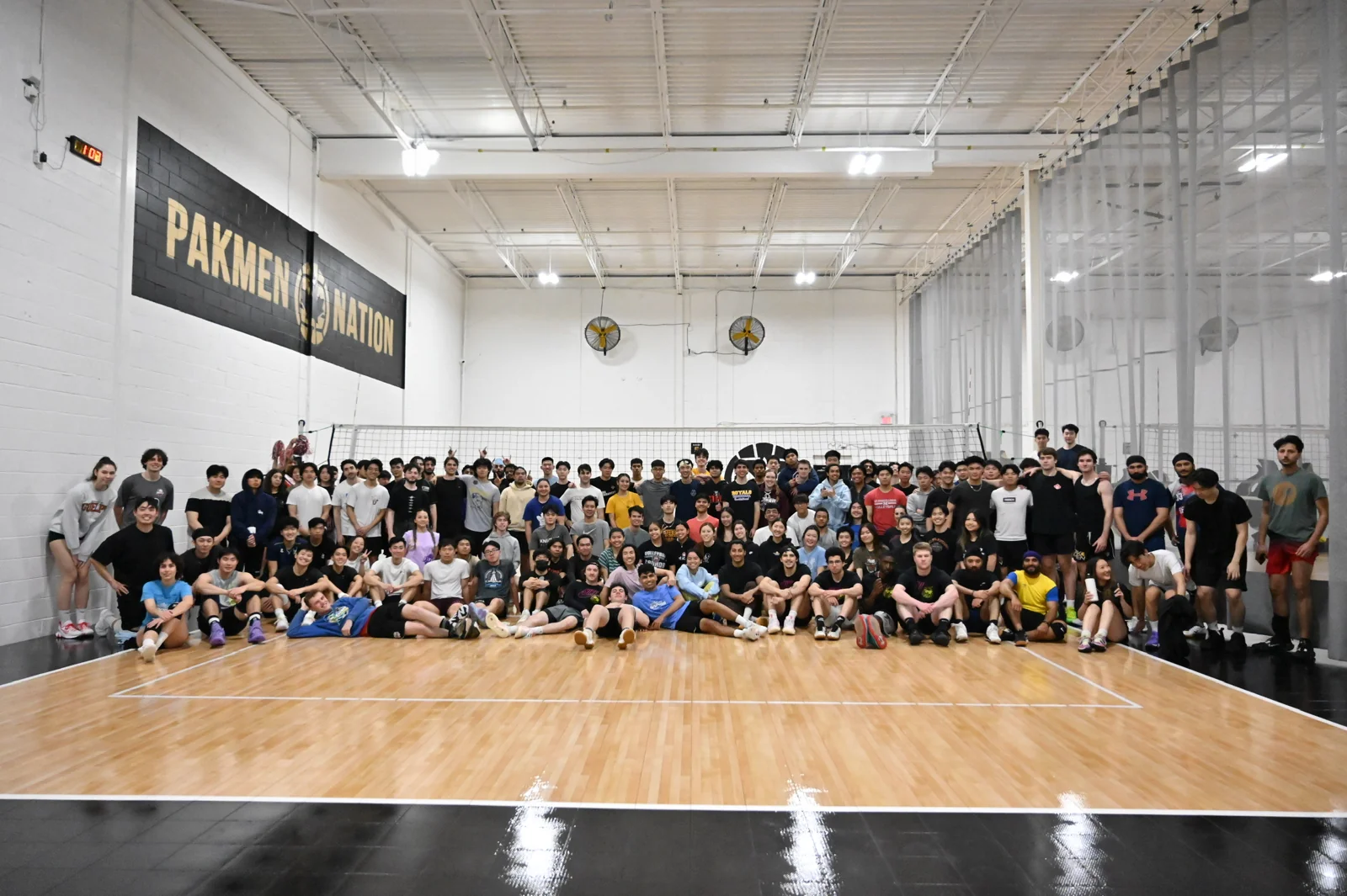 A large group of volleyball players pictured together on an indoor court.