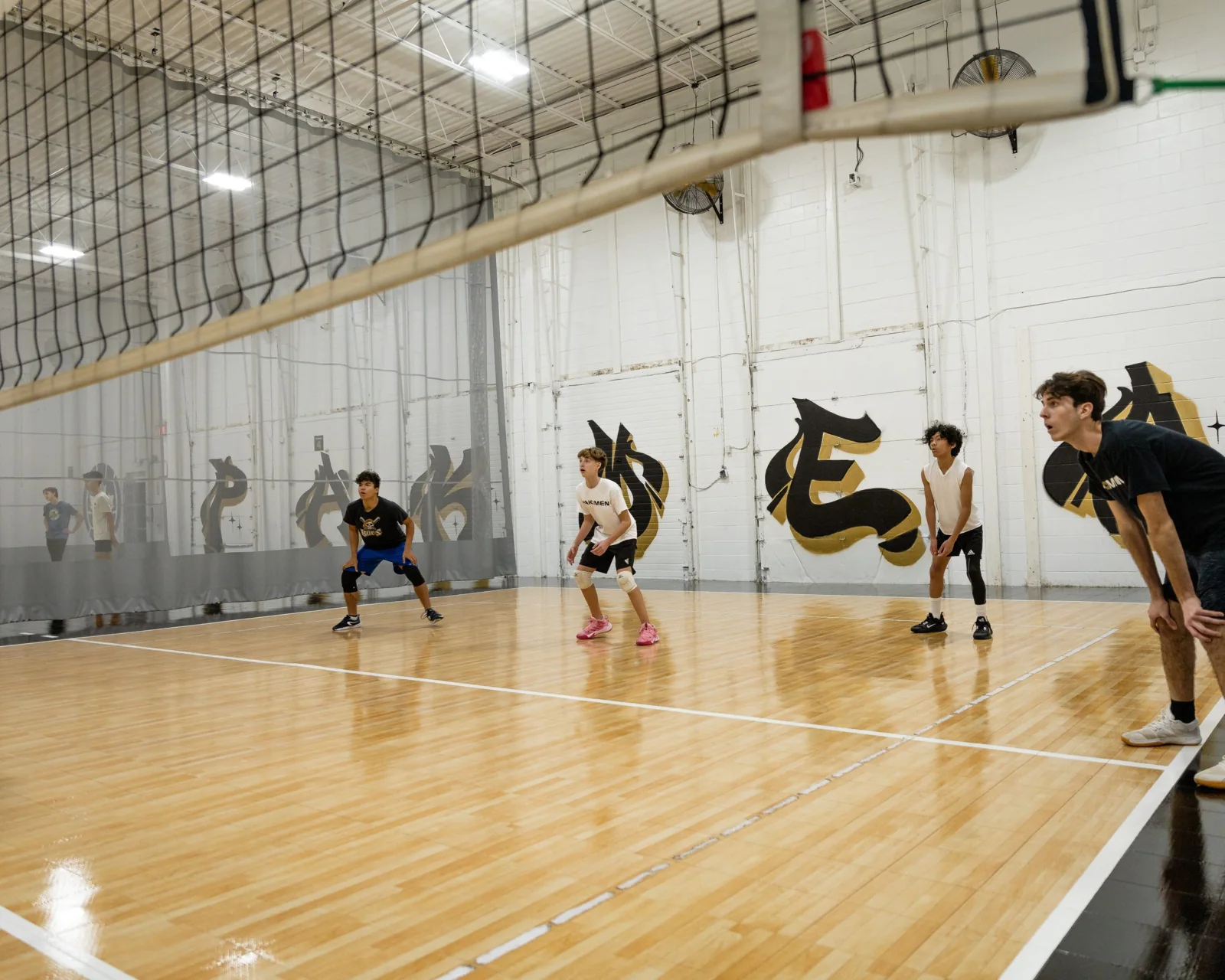 Volleyball players preparing for a rally on an indoor court.